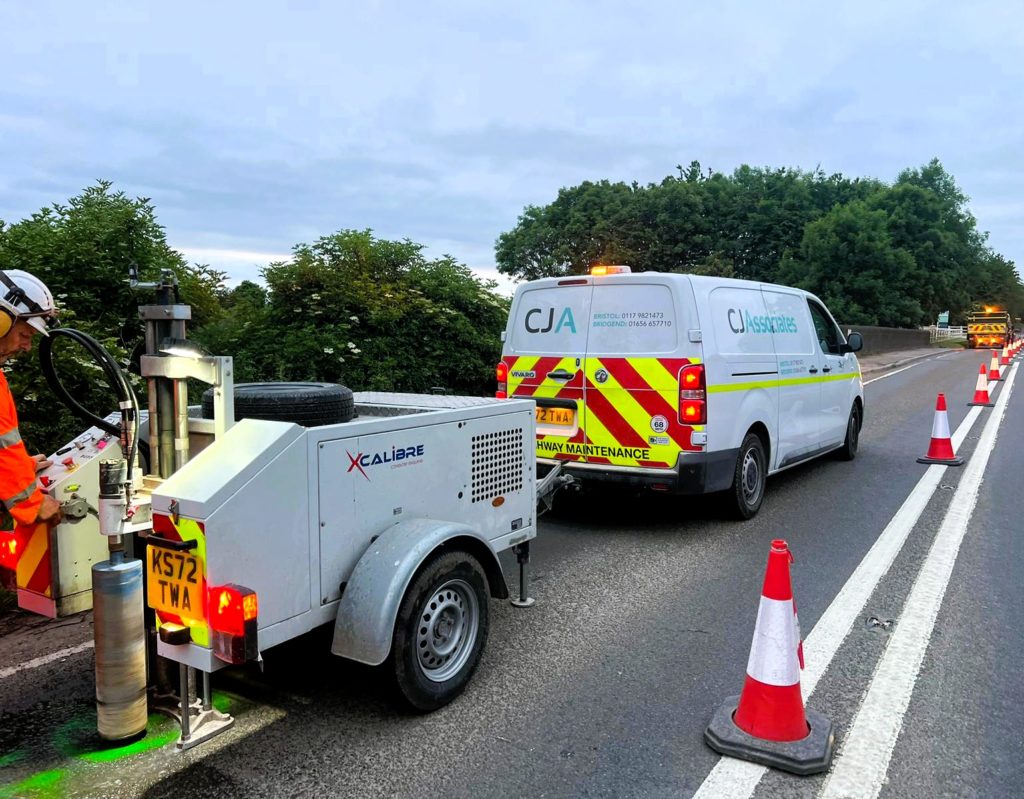 Concrete coring and a CJ Associates van parked on the road, to the left of set out traffic cones.